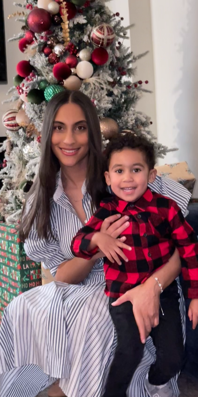 Woman and little boy in holiday attire in front of a Christmas Tree