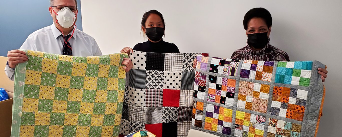 Children's Aid staff with baby quilts made for our Early Childhood program