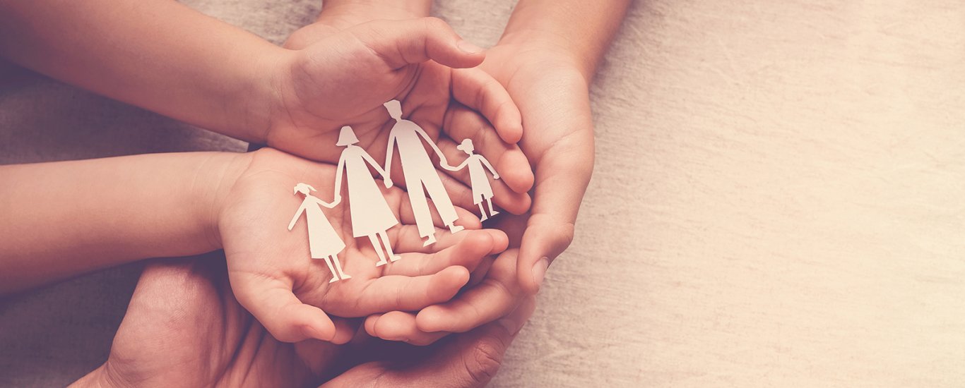 Hands holding a cutout of a family