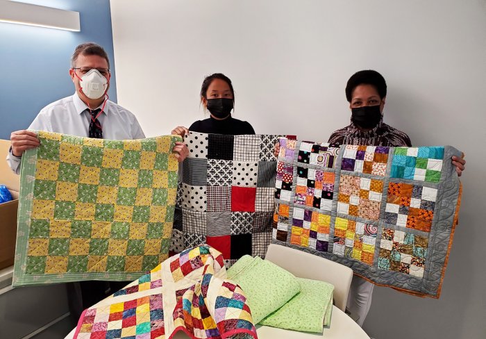 Children's Aid staff with baby quilts made for our Early Childhood program
