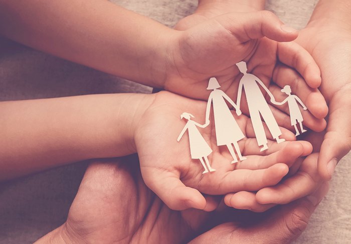 Hands holding a cutout of a family