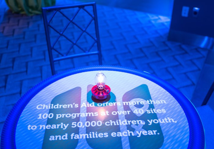 Cocktail tables topped with "badges of honor" by way of Children's Aid facts.