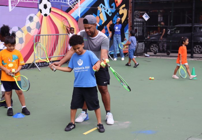 Tennis instructor helping a student with forehand swing