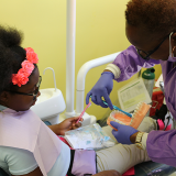 Child learning to brush teeth at dental office