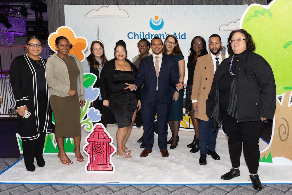 Children's Aid staff at the pop-up book step and repeat with featured youth speaker Emmanuel Ferrerias and Children's Aid President and CEO Phoebe Boyer