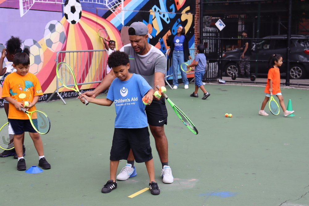 Tennis instructor helping a student with forehand swing